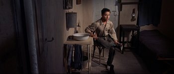 Movie still from “Exodus” (1960), directed by Otto Preminger – A man sitting on a chair next to a sink; Wide shot, High angle