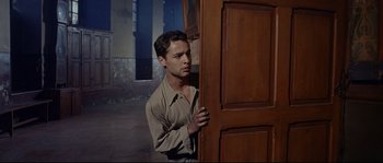 Movie still from “Exodus” (1960), directed by Otto Preminger – A man standing in front of a wooden door; Medium shot, Low angle