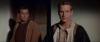 Movie still from “Exodus” (1960), directed by Otto Preminger – A man standing next to another man in front of a door; Close Up shot, Low angle