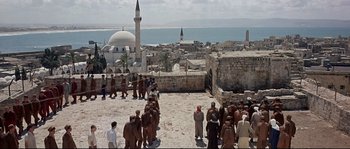 Movie still from “Exodus” (1960), directed by Otto Preminger – A group of people standing on top of a building near the ocean; Extreme Wide shot, High angle