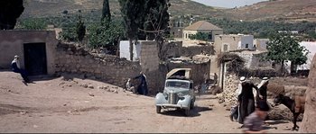 Movie still from “Exodus” (1960), directed by Otto Preminger – An old car parked on the side of the road; Extreme Wide shot, High angle