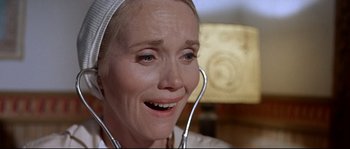 Movie still from “Exodus” (1960), directed by Otto Preminger – An older woman wearing a white hat and holding a stethoscope in her mouth; Close Up shot, Low angle