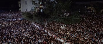 Movie still from “Exodus” (1960), directed by Otto Preminger – A large crowd of people gathered under a tree at night; Extreme Wide shot, High angle
