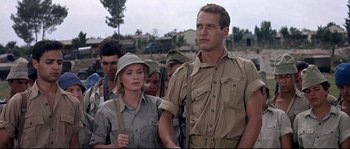 Movie still from “Exodus” (1960), directed by Otto Preminger – A man and a woman are standing in front of a group of people; Medium shot, Low angle