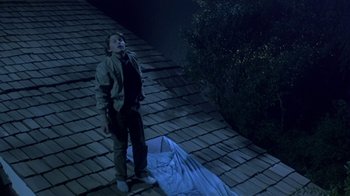 Movie still from “Explorers” (1985), directed by Joe Dante – A man standing on the roof of a building; Wide shot, Overhead angle