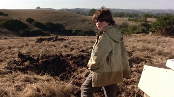 Movie still from “Explorers” (1985), directed by Joe Dante – A young boy in a field with a jacket on; Medium shot, Low angle