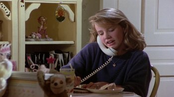 Movie still from “Explorers” (1985), directed by Joe Dante – A young girl sitting at a dining table talking on the phone; Close Up shot, Low angle