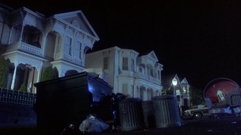 Movie still from “Explorers” (1985), directed by Joe Dante – A night time view of a city street with trash cans; Wide shot, Low angle
