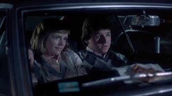 Movie still from “Explorers” (1985), directed by Joe Dante – Two people sitting in the back seat of a car; Medium shot, Over the shoulder angle