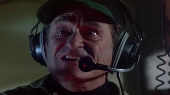 Movie still from “Explorers” (1985), directed by Joe Dante – An older man wearing a green hat and headphones; Close Up shot, Low angle