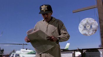 Movie still from “Explorers” (1985), directed by Joe Dante – A man in a uniform reading a newspaper; Medium shot, Low angle
