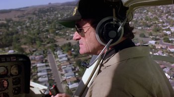 Movie still from “Explorers” (1985), directed by Joe Dante – An older man flying a helicopter over a city; Medium shot, Low angle