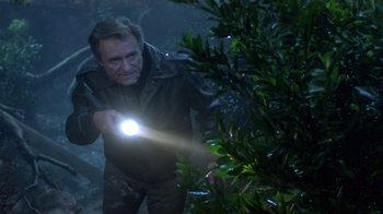 Movie still from “Explorers” (1985), directed by Joe Dante – A man holding a flashlight while standing next to a tree; Medium shot, High angle