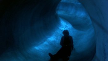 Movie still from “Explorers” (1985), directed by Joe Dante – A person sitting in a cave looking up at the sky; Extreme Wide shot, High angle
