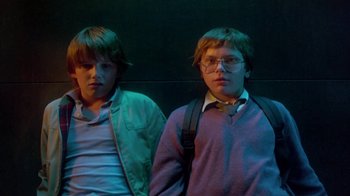 Movie still from “Explorers” (1985), directed by Joe Dante – Two young men standing next to each other in front of a wall; Medium shot, Low angle