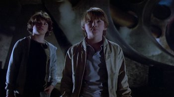 Movie still from “Explorers” (1985), directed by Joe Dante – Two young men standing next to each other in front of a wall; Medium shot, Low angle