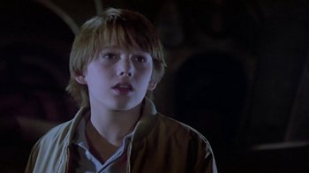Movie still from “Explorers” (1985), directed by Joe Dante – A young man with a long blonde hair wearing a brown jacket; Close Up shot, Low angle
