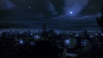 Movie still from “Explorers” (1985), directed by Joe Dante – A view of a city at night with a full moon in the distance; Extreme Wide shot, High angle