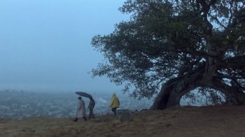 Movie still from “Explorers” (1985), directed by Joe Dante – Two people walking on a hill under a tree; Extreme Wide shot, Low angle