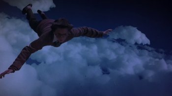 Movie still from “Explorers” (1985), directed by Joe Dante – A man flying through the air while holding onto a parachute; Wide shot, Overhead angle