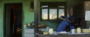 Movie still from “Eye in the Sky” (2015), directed by Gavin Hood – A woman in a blue dress in front of a window; Medium shot, Low angle