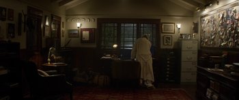 Movie still from “Eye in the Sky” (2015), directed by Gavin Hood – A man standing in front of a window looking outside; Wide shot, Low angle