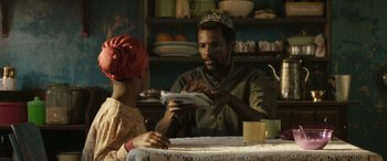 Movie still from “Eye in the Sky” (2015), directed by Gavin Hood – A man and a woman sitting at a dining table; Medium shot, Over the shoulder angle