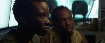 Movie still from “Eye in the Sky” (2015), directed by Gavin Hood – Two people sitting next to each other on a bus; Close Up shot, Over the shoulder angle