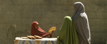 Movie still from “Eye in the Sky” (2015), directed by Gavin Hood – Two women are sitting at a table with bread on it; Medium shot, Over the shoulder angle