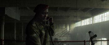 Movie still from “Eye in the Sky” (2015), directed by Gavin Hood – A man talking on a phone while wearing a red beret; Medium shot, Low angle