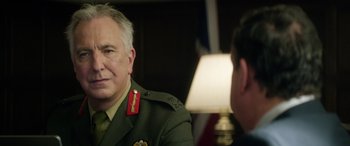 Movie still from “Eye in the Sky” (2015), directed by Gavin Hood – A man in a military uniform sitting in front of another man; Close Up shot, Over the shoulder angle