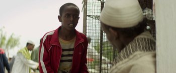 Movie still from “Eye in the Sky” (2015), directed by Gavin Hood – A young man talking to a woman in a red jacket; Close Up shot, Over the shoulder angle