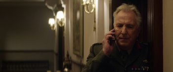 Movie still from “Eye in the Sky” (2015), directed by Gavin Hood – An older man talking on a cell phone in a room; Close Up shot, Low angle