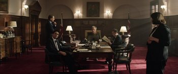 Movie still from “Eye in the Sky” (2015), directed by Gavin Hood – A group of men sitting at a table in a room; Wide shot, Low angle