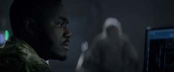 Movie still from “Eye in the Sky” (2015), directed by Gavin Hood – A man's face in a dark room; Close Up shot, Over the shoulder angle