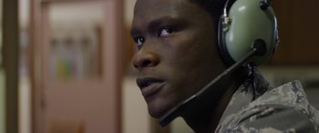 Movie still from “Eye in the Sky” (2015), directed by Gavin Hood – A person wearing a headset; Close Up shot, Over the shoulder angle