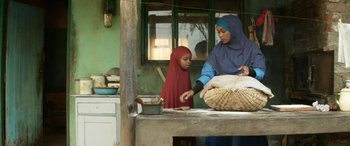 Movie still from “Eye in the Sky” (2015), directed by Gavin Hood – A woman and a child are preparing food in a kitchen; Medium shot, Low angle
