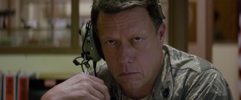 Movie still from “Eye in the Sky” (2015), directed by Gavin Hood – A man in military fatigues holding a radio; Close Up shot, High angle