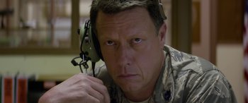 Movie still from “Eye in the Sky” (2015), directed by Gavin Hood – A man in military fatigues holding a pair of ear phones; Close Up shot, High angle