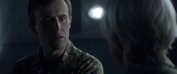 Movie still from “Eye in the Sky” (2015), directed by Gavin Hood – A man in a military uniform talking to another man; Close Up shot, Over the shoulder angle