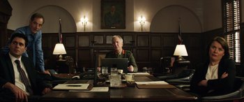 Movie still from “Eye in the Sky” (2015), directed by Gavin Hood – An older man sitting in front of a computer; Medium shot, Low angle