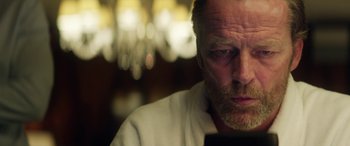 Movie still from “Eye in the Sky” (2015), directed by Gavin Hood – An older man looking at his cell phone; Close Up shot, Low angle