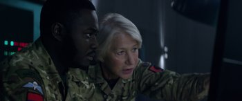 Movie still from “Eye in the Sky” (2015), directed by Gavin Hood – A man and a woman in military uniforms looking intently at each other; Close Up shot, Over the shoulder angle