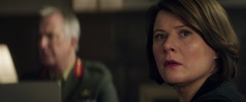Movie still from “Eye in the Sky” (2015), directed by Gavin Hood – A person with short black hair; Close Up shot, Over the shoulder angle