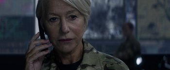 Movie still from “Eye in the Sky” (2015), directed by Gavin Hood – An older woman in a military uniform looking at the camera; Close Up shot, Over the shoulder angle