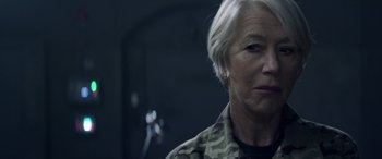 Movie still from “Eye in the Sky” (2015), directed by Gavin Hood – An older woman in camouflage jacket looking at the camera; Close Up shot, Over the shoulder angle