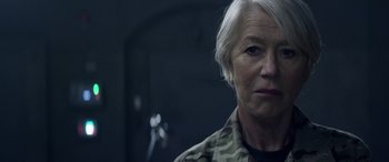 Movie still from “Eye in the Sky” (2015), directed by Gavin Hood – An older woman in a camouflage jacket looking at the camera; Close Up shot, Over the shoulder angle