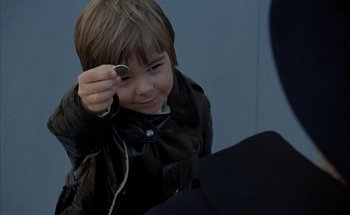 Movie still from “F for Fake” (1973), directed by François Reichenbach – A young boy is holding up a pair of headphones; Close Up shot, High angle