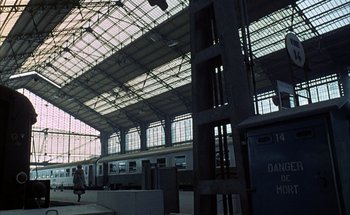 Movie still from “F for Fake” (1973), directed by François Reichenbach – A train station with a train on the tracks; Extreme Wide shot, Low angle