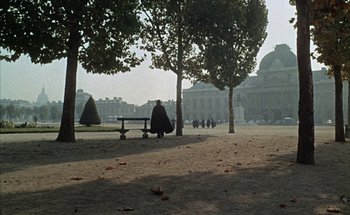 Movie still from “F for Fake” (1973), directed by François Reichenbach – A person sitting on a bench in a park; Extreme Wide shot, High angle